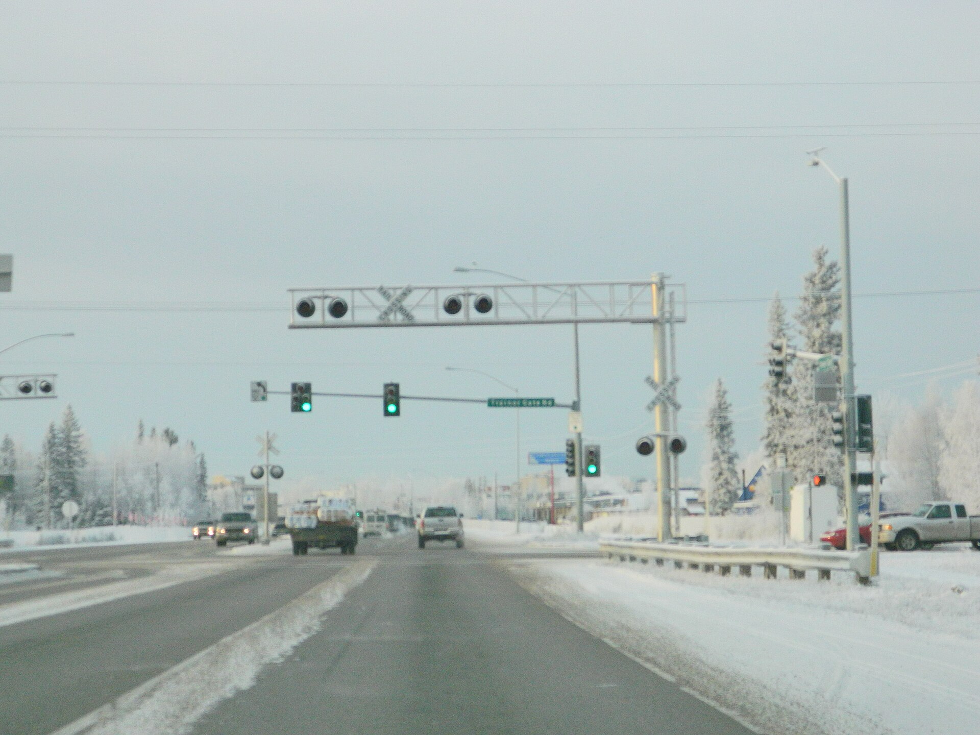 Photo of the snowy Steese Highway southbound at Trainor Gate Road in Fairbanks, Alaska, with frosted spruce and a rail crossing
